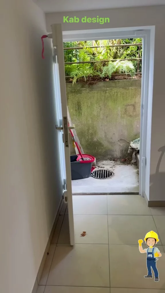 Cave rénovée avec carrelage clair et porte ouverte sur la cour extérieure