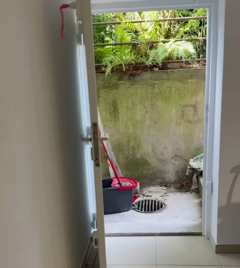 Cave rénovée avec carrelage clair et porte ouverte sur la cour extérieure