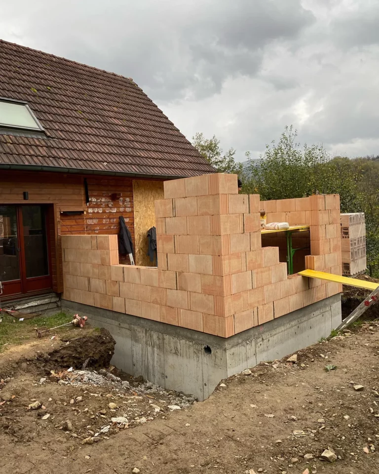 Extension d'une maison en cours de construction : murs en briques montés sur une dalle béton