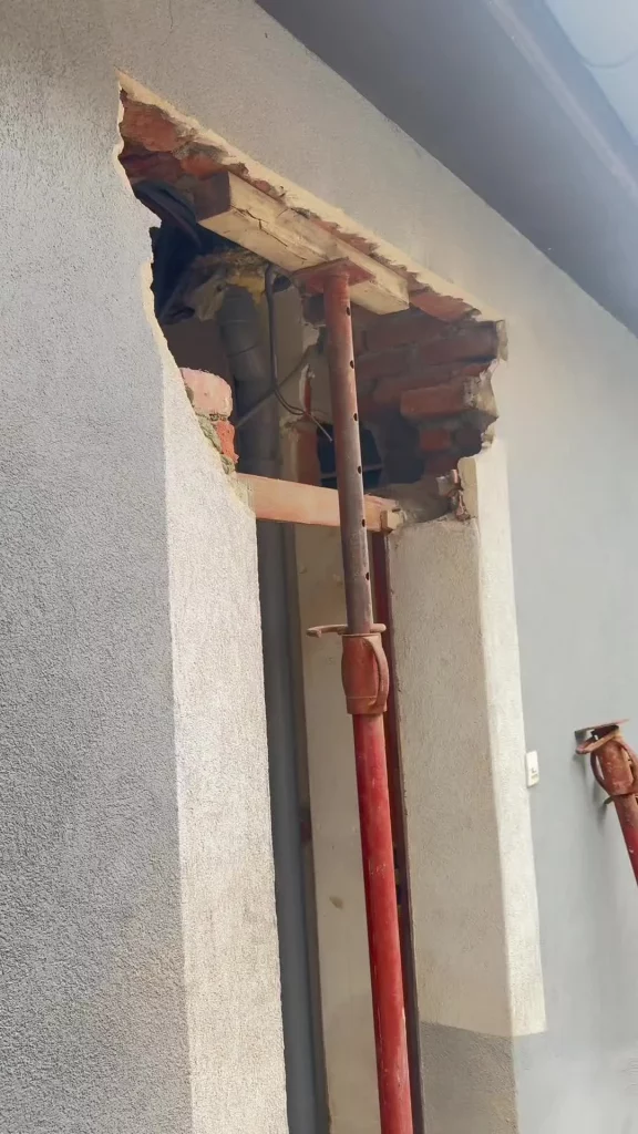 Ouverture d'une porte d'entrée en cours de rehausse, soutenue par des étais métalliques