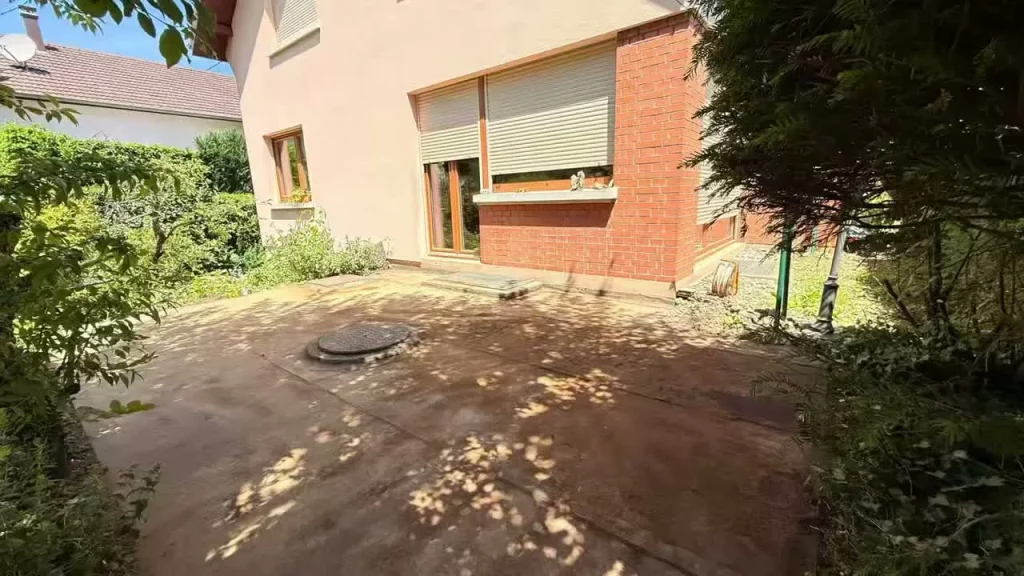 Terrasse devant une maison en briques, au-dessus de l'ancien local de cuve à fioul transformé en rangement