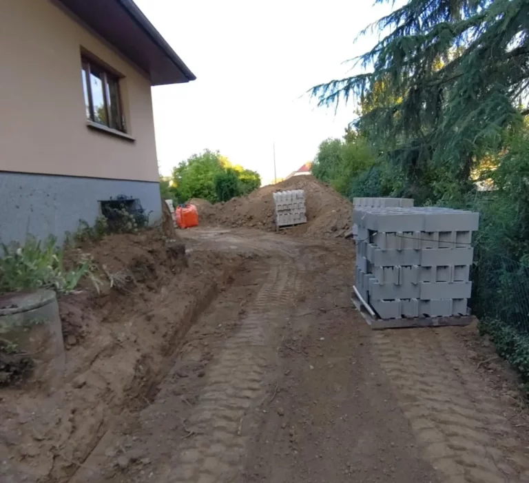 Démarrage d'un terrassement le long d'une maison, avec des palettes de blocs béton prêtes à poser